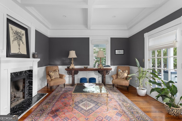 sitting room with coffered ceiling, a healthy amount of sunlight, beam ceiling, and a premium fireplace