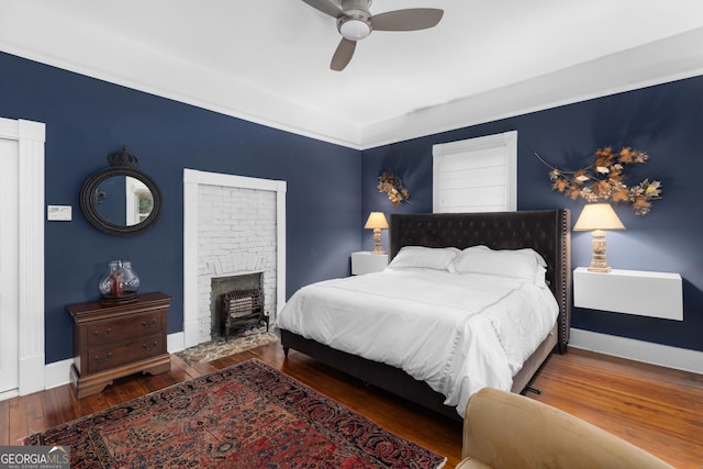 bedroom featuring wood-type flooring, a fireplace, and ceiling fan