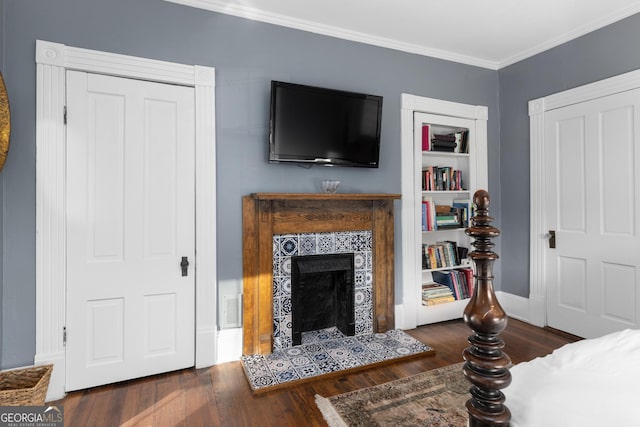 living room with built in shelves, ornamental molding, dark hardwood / wood-style floors, and a fireplace