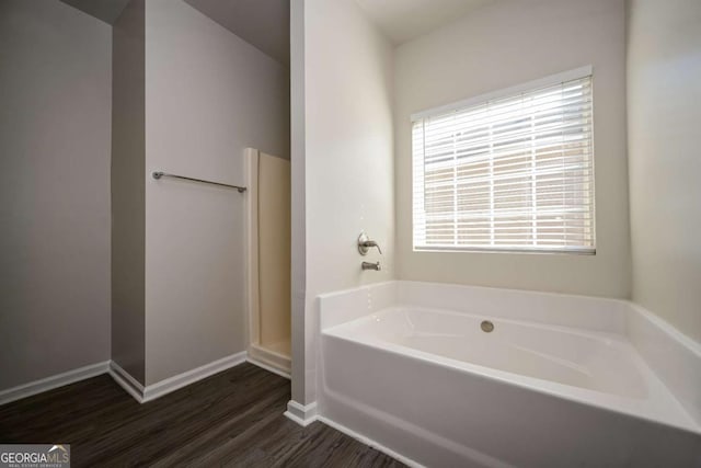 bathroom with wood-type flooring and a bath