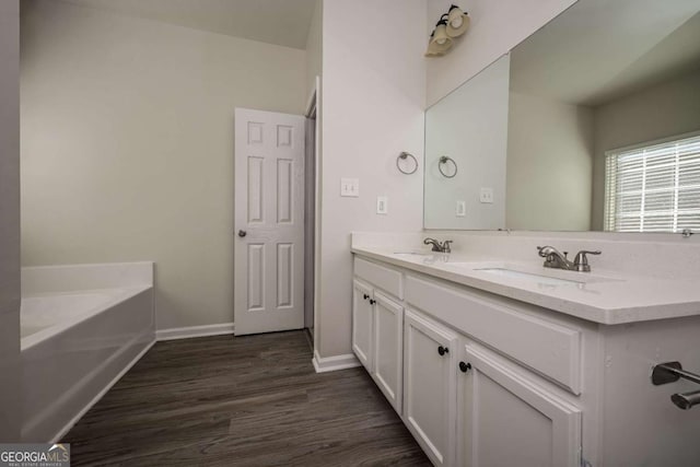 bathroom with hardwood / wood-style flooring, vanity, and a bathing tub