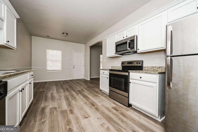 kitchen with white cabinets, light wood-type flooring, stone countertops, and stainless steel appliances