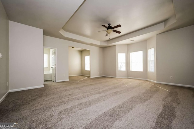 carpeted spare room featuring ceiling fan and a raised ceiling