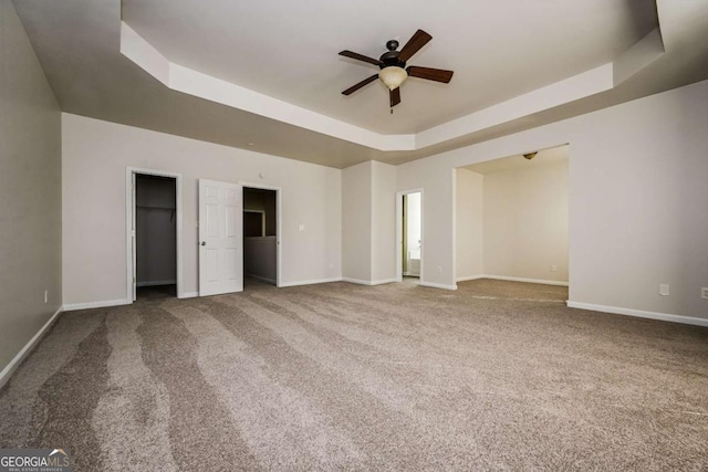 unfurnished bedroom featuring ceiling fan, carpet, and a tray ceiling