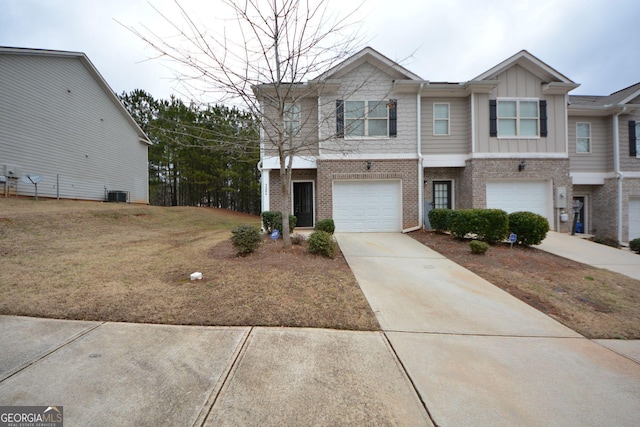 view of property featuring a front yard, central AC unit, and a garage