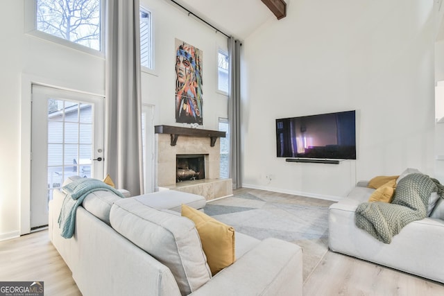 living room with beamed ceiling, a high ceiling, and light wood-type flooring