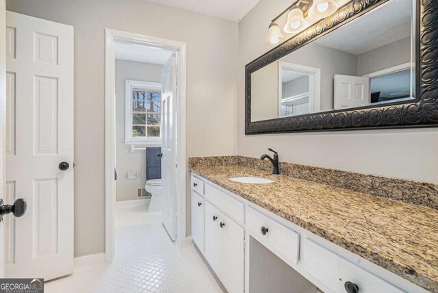 bedroom with dark wood-type flooring, ceiling fan, and ensuite bath