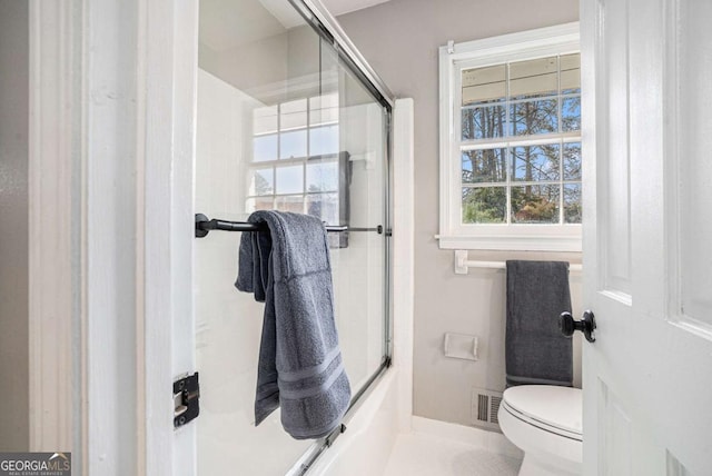 bathroom with a shower with door and toilet