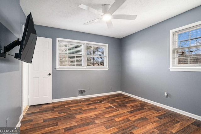 empty room with a textured ceiling, ceiling fan, and dark hardwood / wood-style floors