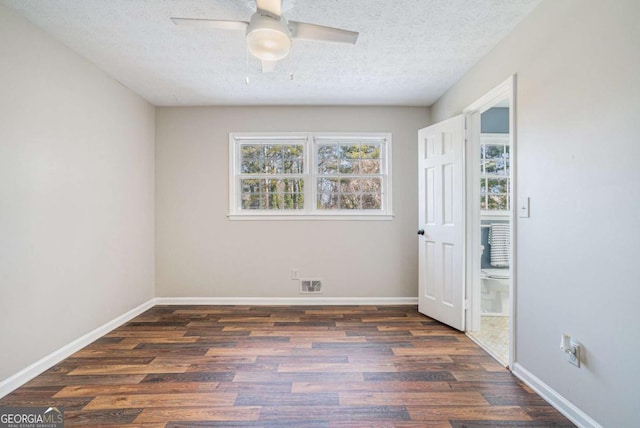 empty room with ceiling fan, dark wood-type flooring, and a textured ceiling