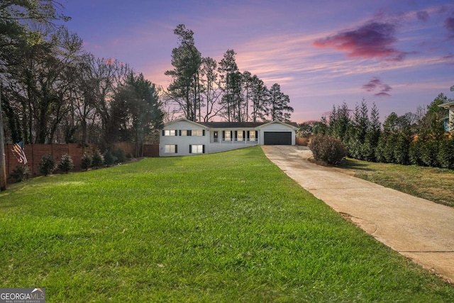 ranch-style home featuring a garage and a lawn