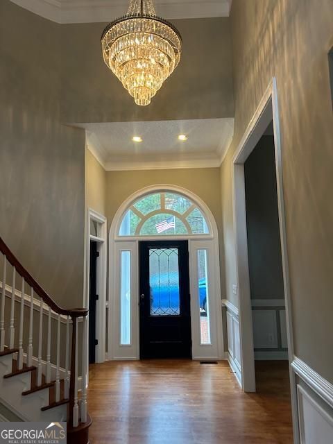 foyer entrance featuring ornamental molding, a chandelier, and light wood-type flooring