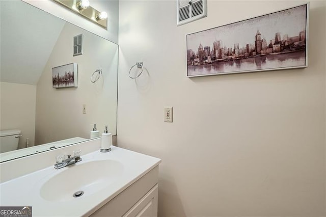 bathroom with toilet, vanity, and vaulted ceiling