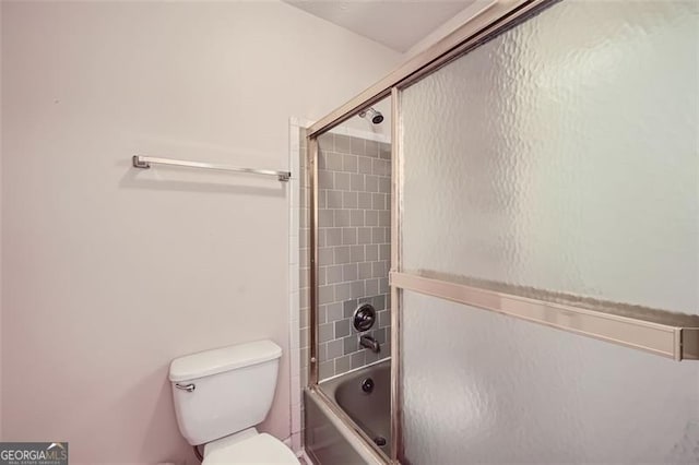 bathroom featuring toilet and shower / bath combination with glass door