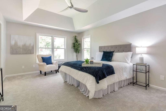 bedroom featuring ceiling fan, a raised ceiling, and light colored carpet