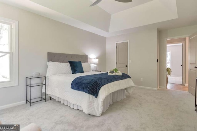 carpeted bedroom with ceiling fan and a raised ceiling