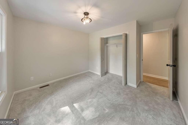 unfurnished bedroom featuring a closet and light carpet