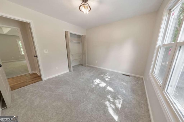 unfurnished bedroom featuring light colored carpet and a closet