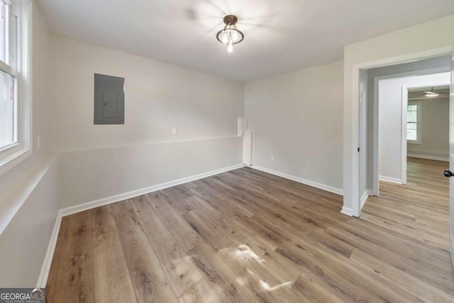 empty room with electric panel and light wood-type flooring