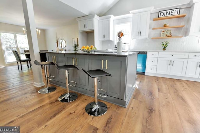 kitchen featuring a kitchen island, white cabinetry, a kitchen bar, and stainless steel dishwasher