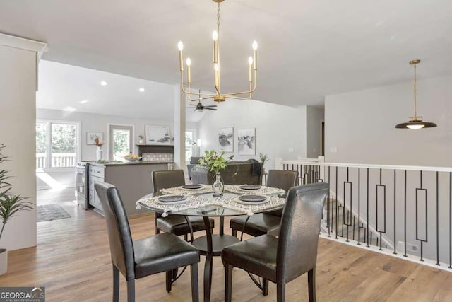 dining space with light hardwood / wood-style floors, ceiling fan with notable chandelier, and vaulted ceiling