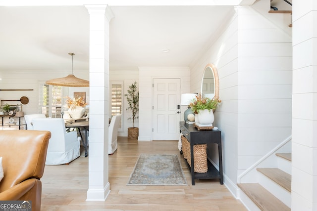 foyer featuring ornamental molding, light hardwood / wood-style floors, and ornate columns