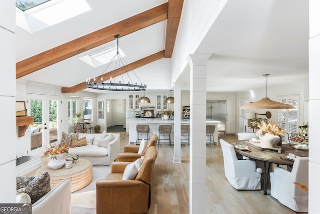 living room featuring lofted ceiling with skylight, light hardwood / wood-style floors, and ornate columns