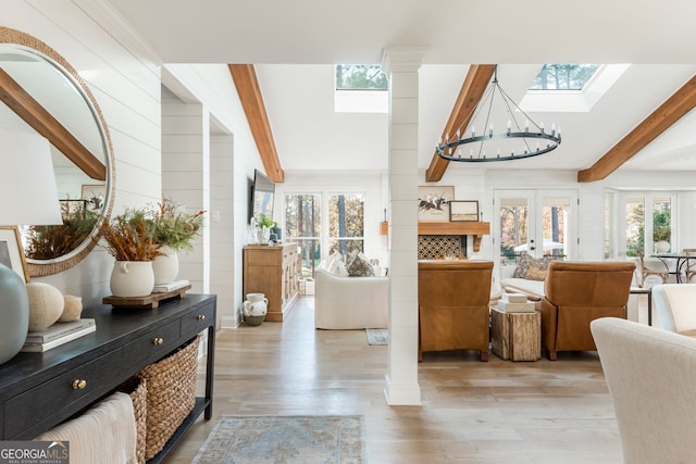 interior space with a skylight, decorative columns, light hardwood / wood-style floors, french doors, and beamed ceiling