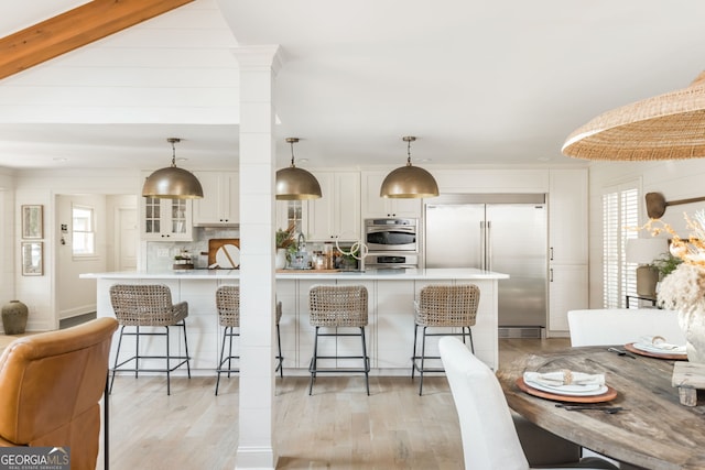 kitchen with stainless steel appliances, tasteful backsplash, a kitchen bar, and decorative light fixtures