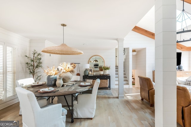 dining room featuring crown molding, light hardwood / wood-style flooring, beamed ceiling, and ornate columns