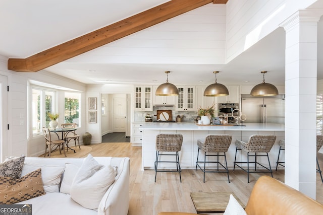 kitchen with built in fridge, pendant lighting, white cabinets, decorative backsplash, and beam ceiling