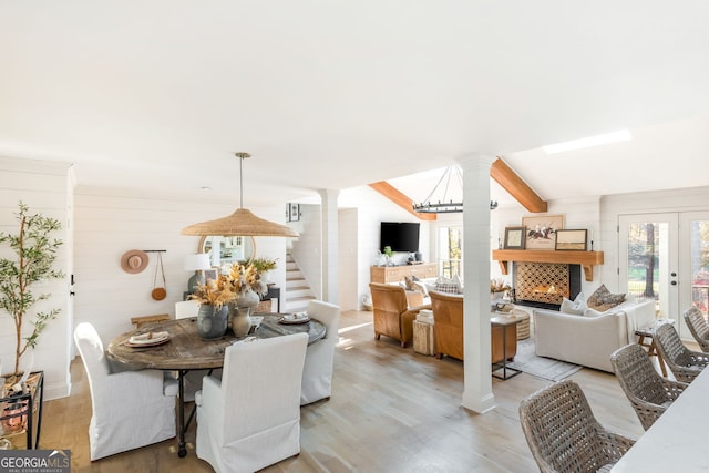 dining space featuring light hardwood / wood-style floors, french doors, and ornate columns