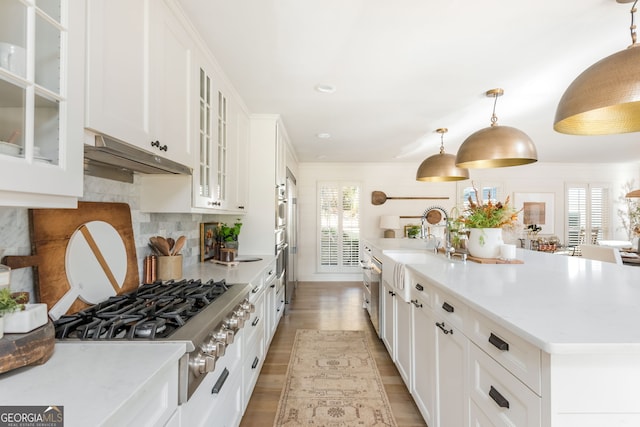 kitchen with decorative light fixtures, an island with sink, sink, white cabinets, and stainless steel gas cooktop