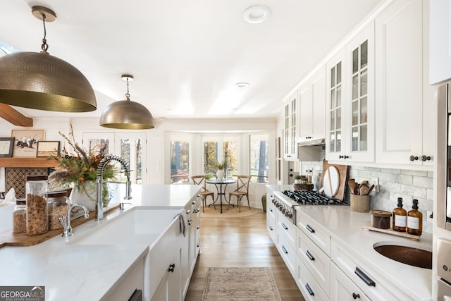 kitchen featuring pendant lighting, backsplash, sink, and white cabinets