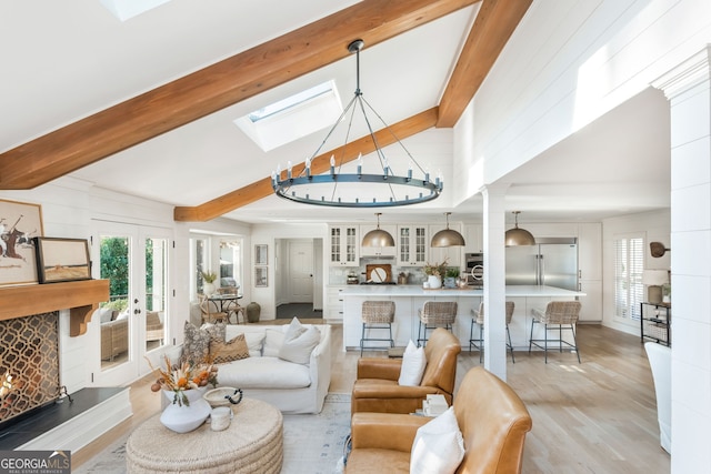 living room featuring a skylight, high vaulted ceiling, light hardwood / wood-style floors, french doors, and beamed ceiling