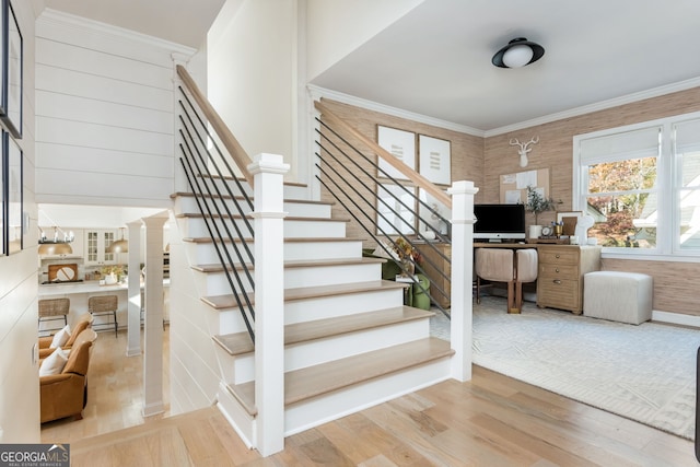 staircase with wood-type flooring and ornamental molding