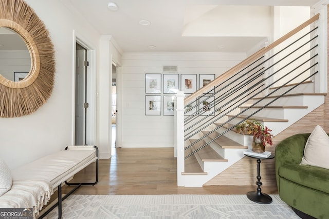 staircase with crown molding and hardwood / wood-style flooring