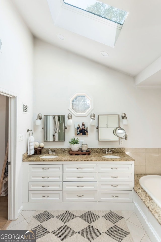 bathroom featuring tile patterned floors, a skylight, vanity, and a washtub