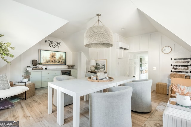 dining room with lofted ceiling, a wall mounted air conditioner, and light hardwood / wood-style floors