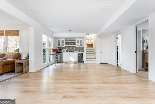 living room with bar, beverage cooler, and light hardwood / wood-style flooring