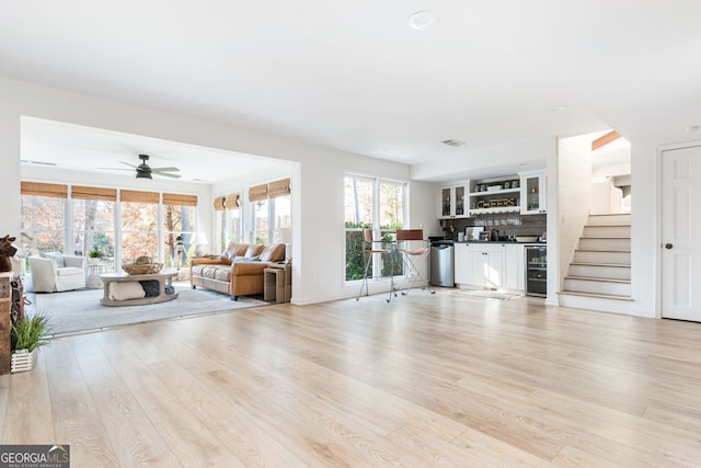 unfurnished living room featuring ceiling fan, bar area, and light hardwood / wood-style floors