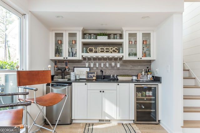 bar with refrigerator, white cabinetry, sink, beverage cooler, and backsplash