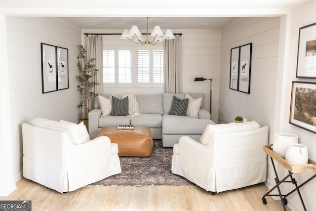 living room with an inviting chandelier, wooden walls, and hardwood / wood-style floors