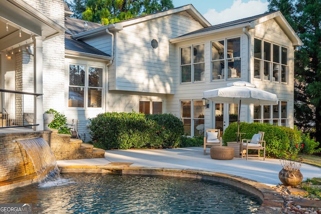 rear view of house featuring pool water feature and a patio area