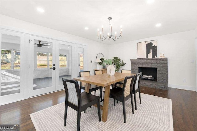 dining area with a fireplace, dark hardwood / wood-style flooring, a notable chandelier, and french doors