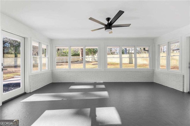 unfurnished sunroom featuring ceiling fan and plenty of natural light