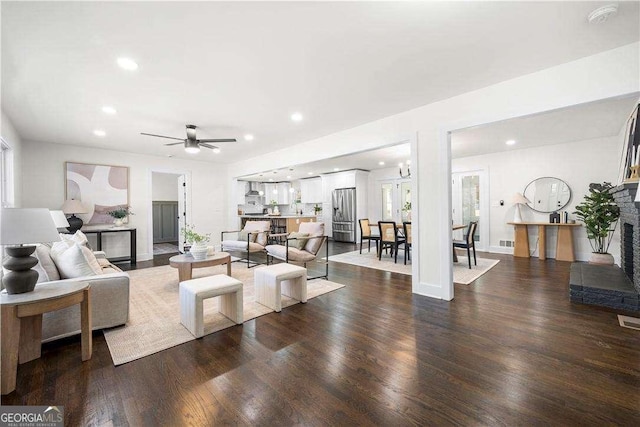 living room featuring ceiling fan, dark wood-type flooring, and a fireplace