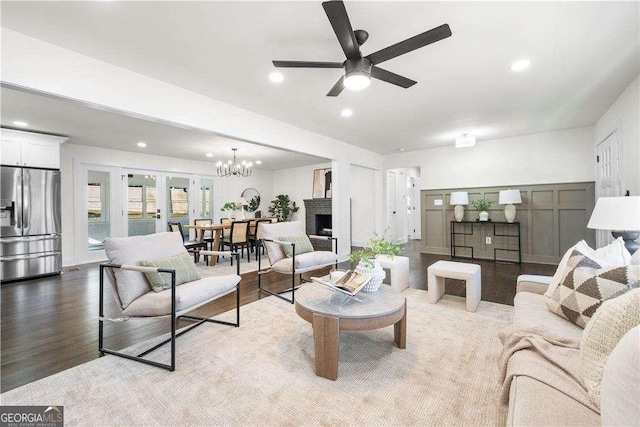 living room featuring french doors, ceiling fan with notable chandelier, light hardwood / wood-style floors, and a fireplace