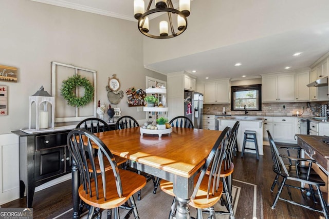 dining area with sink, dark hardwood / wood-style flooring, ornamental molding, and a notable chandelier