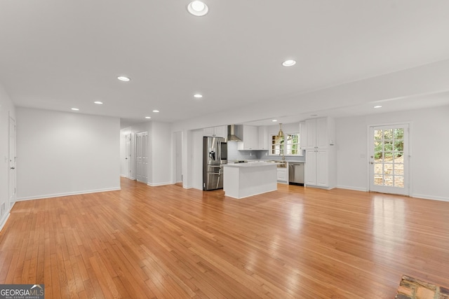 unfurnished living room with light wood-type flooring, recessed lighting, and baseboards